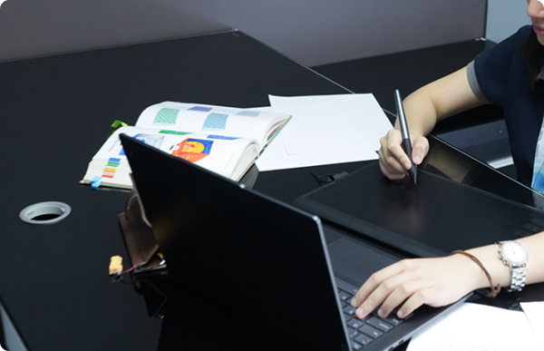 A designer utilising digital tools and physical references to create content in a modern studio setting.